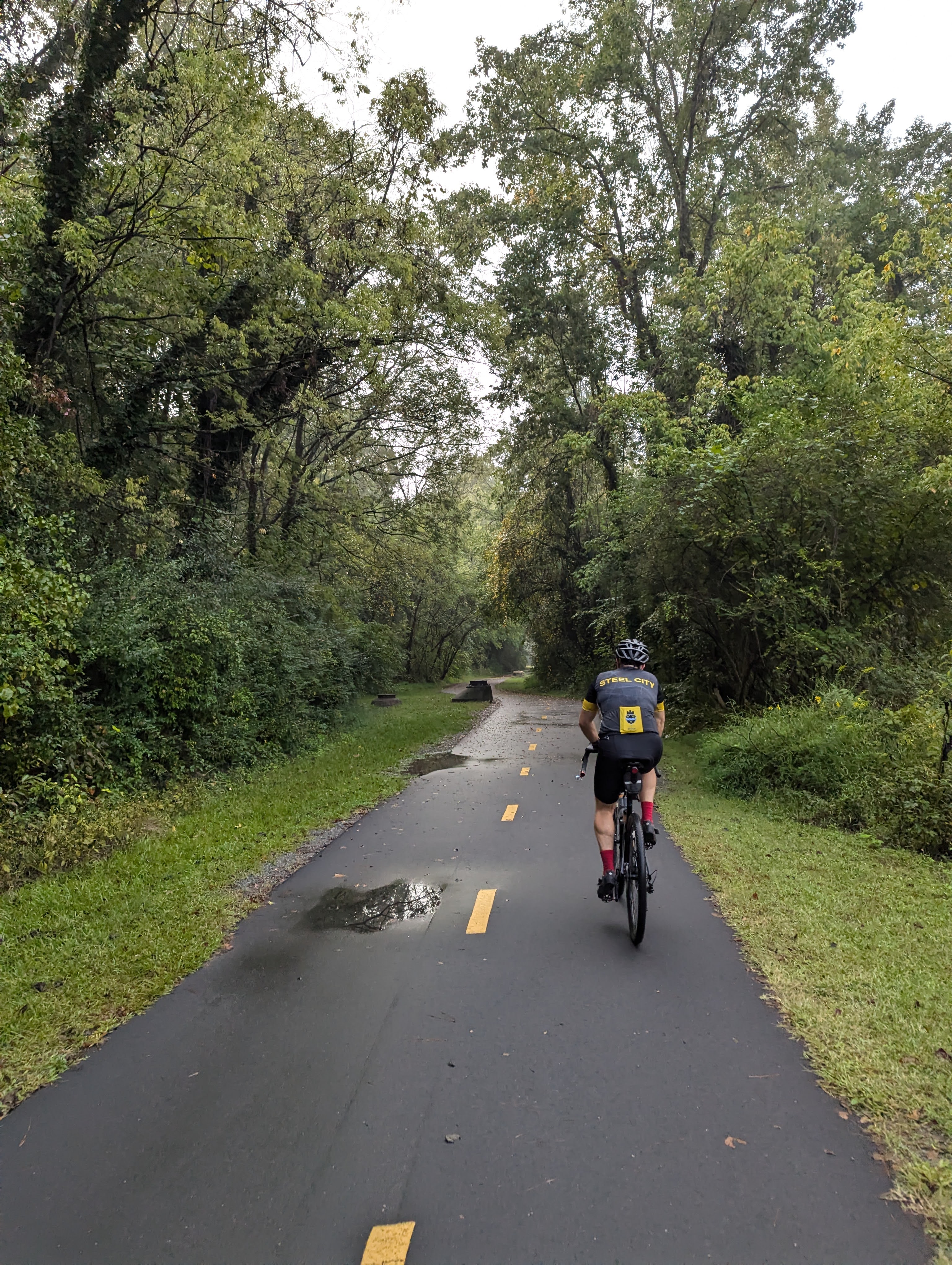 A cyclist riding on a wet paved trail during DjangoCon US 2024