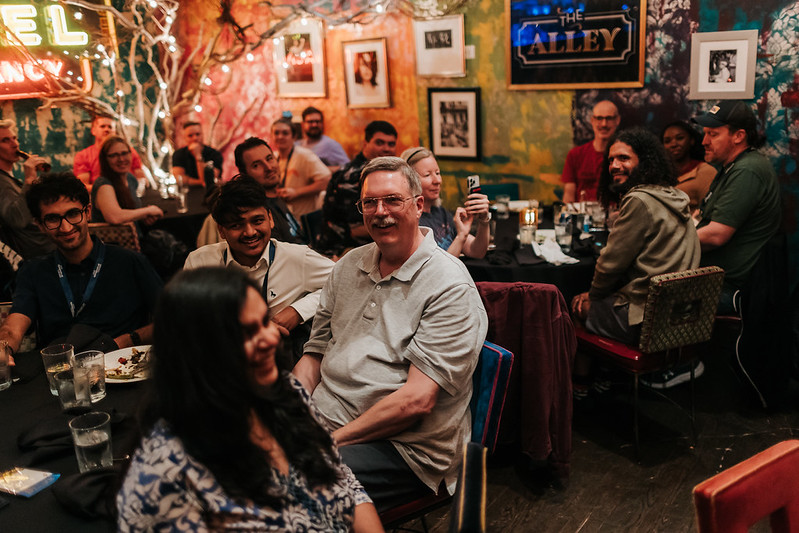 Attendees laughing and socializing at a restaurant during DjangoCon US 2025