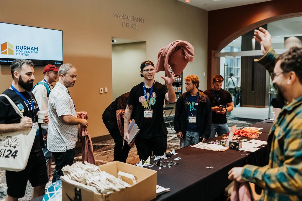 Volunteers at DjangoCon US hand out t-shirts to excited attendees